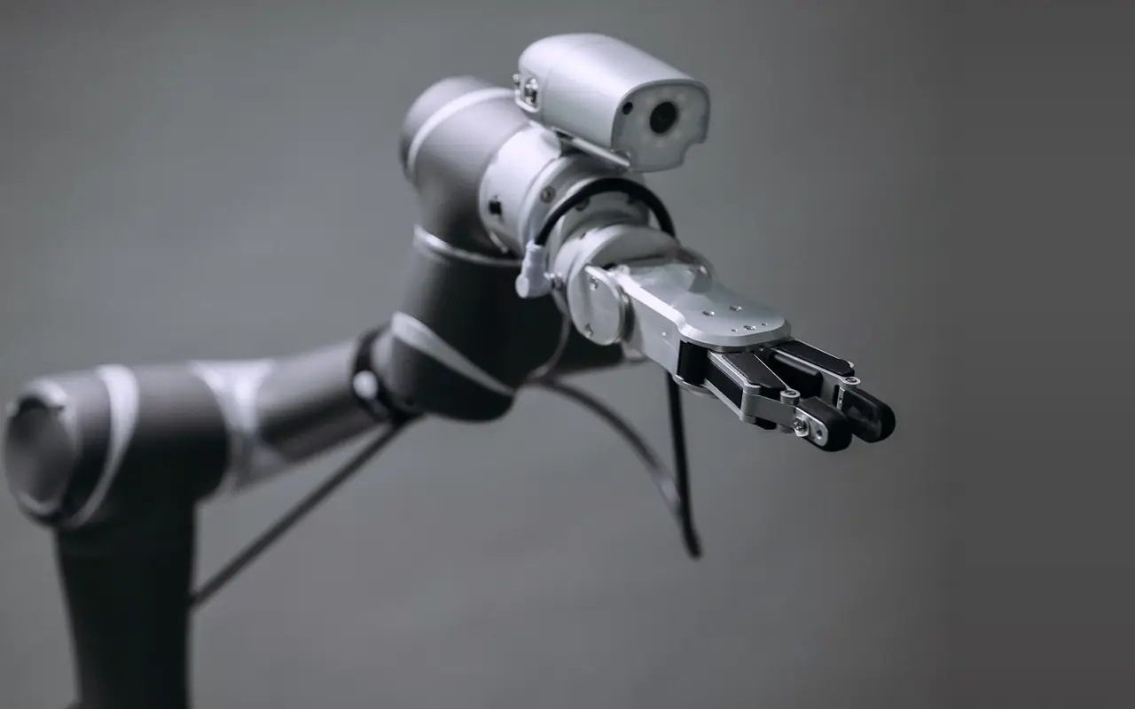 Collaborative robot arm with a camera and gripper against a grey studio background