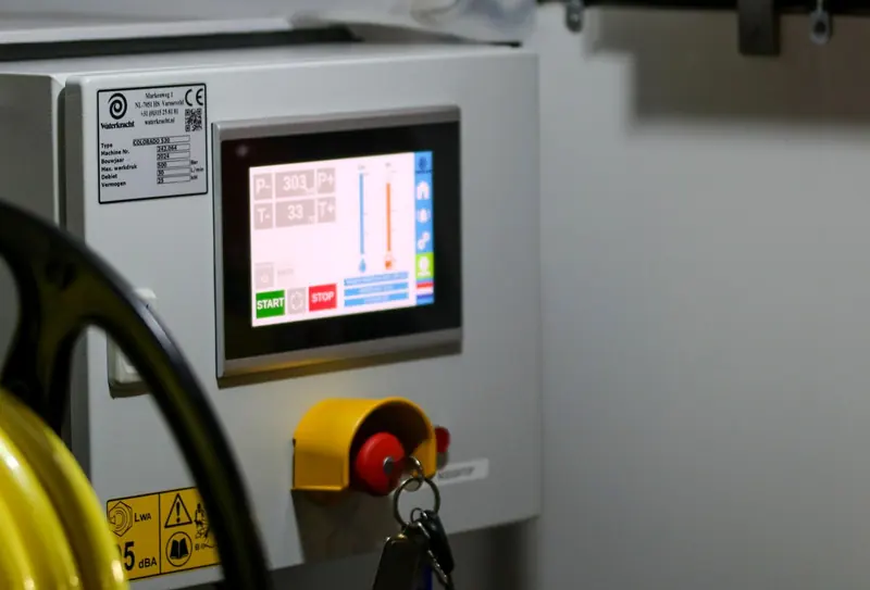 Touch-screen operator panel mounted on a machine next to an emergency stop
