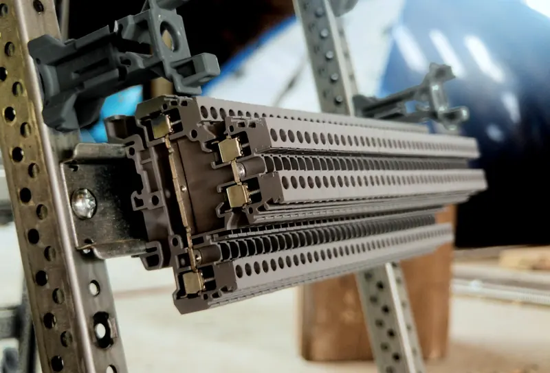 Rows of grey DIN-rail terminal blocks mounted on a slotted steel frame